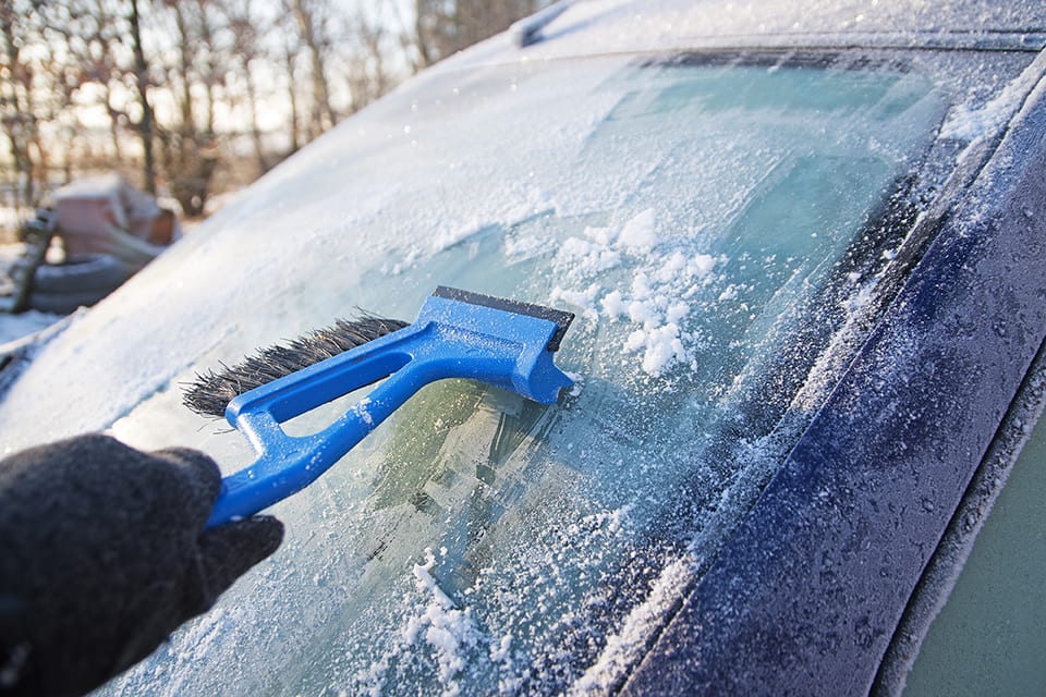 a person scrapping ice off a windshield