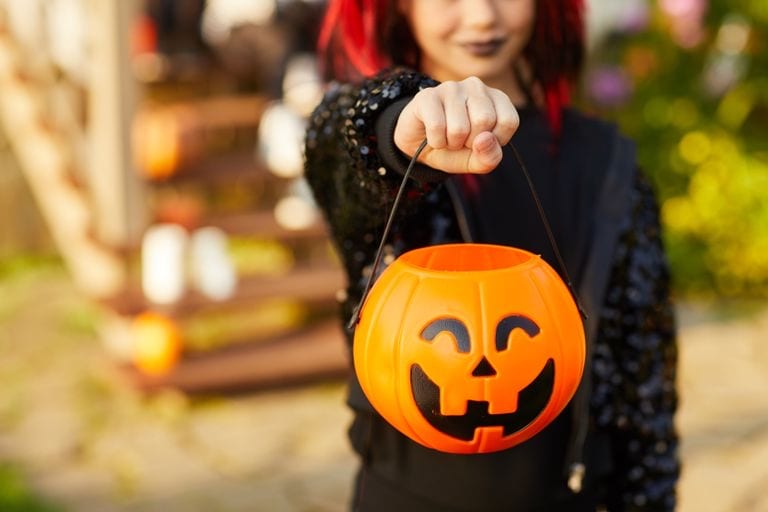 a girl in Halloween costume holding a plastic pumpkin